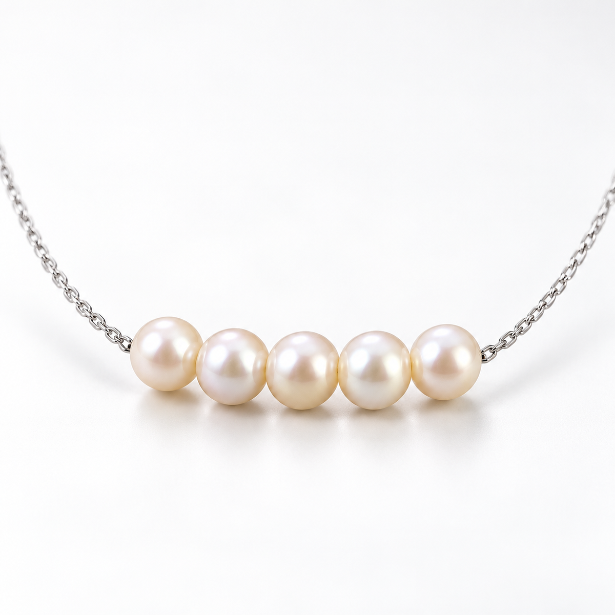 Close-up of five natural pearls arranged along the centre of a silver-plated necklace