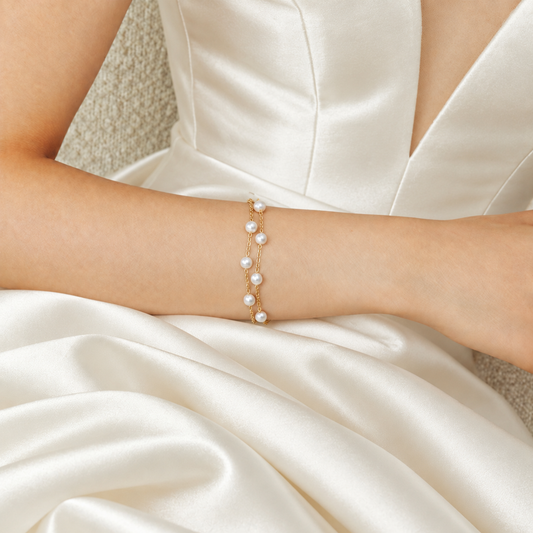 Double-strand gold pearl bracelet worn against an ivory satin wedding gown