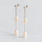 Angled view of the pair showing stud posts, fine chains and two pearls per earring