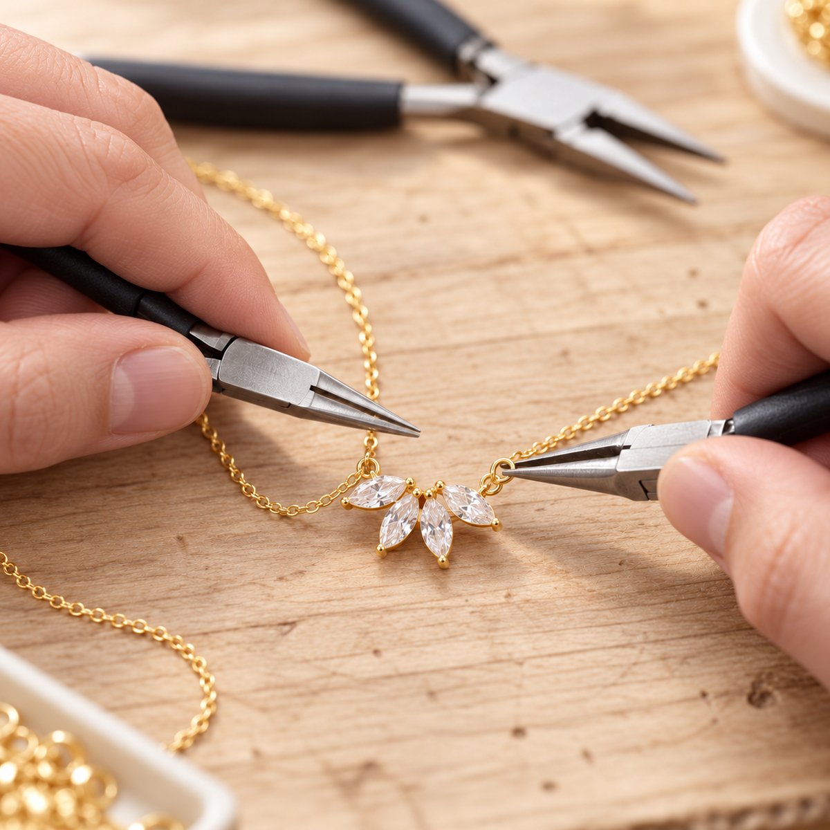 Illustrative assembly scene showing pliers at the connecting ring of a gold-coloured flower petal necklace