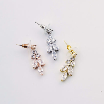 Three pairs of leaf drop earrings in silver, gold, and rose gold on a white background