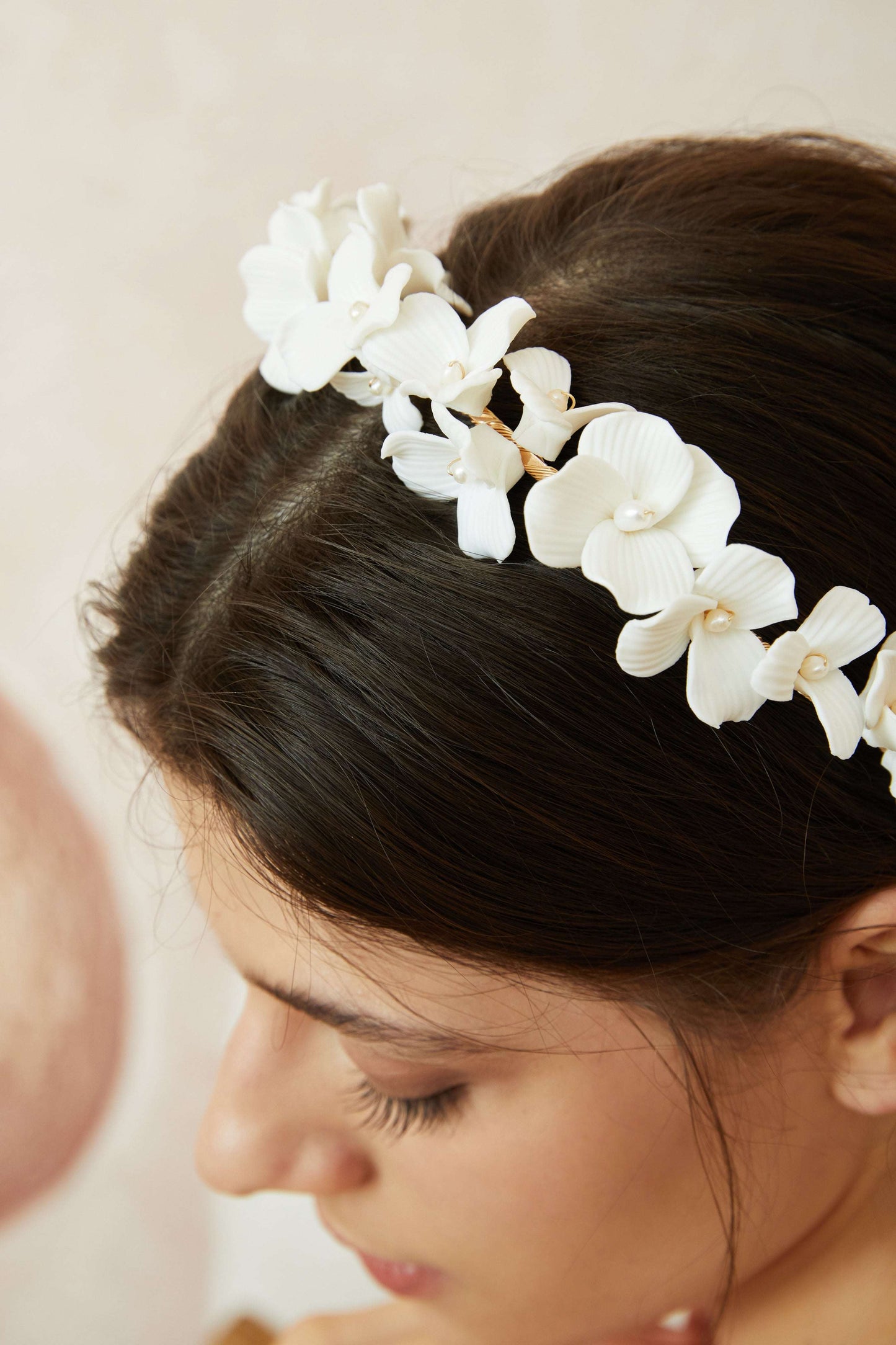 Model wearing the matching delicate pearl and porcelain floral bridal headband