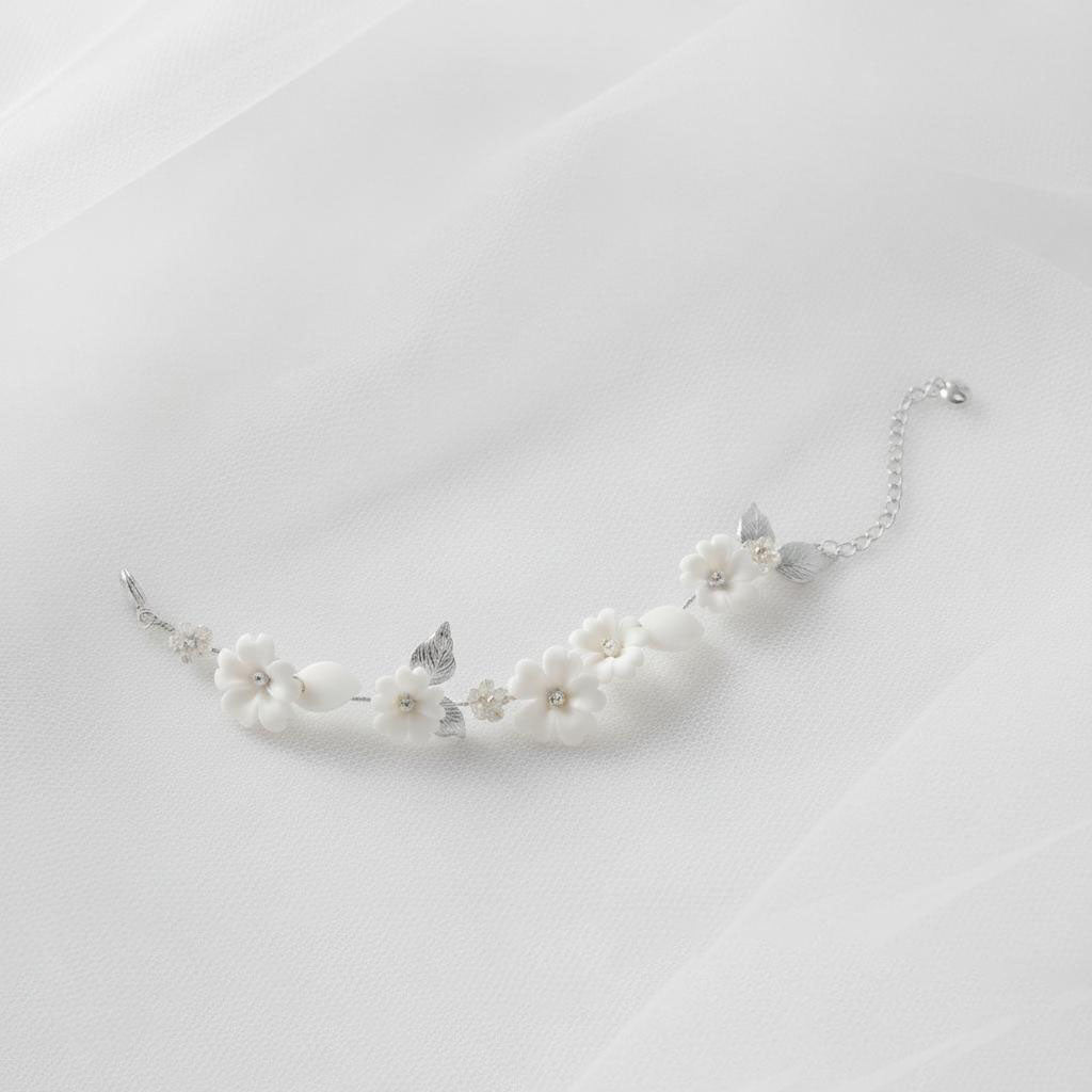 Adjustable floral bracelet with white ceramic blooms and leaf accents, gold chain bridal wrist jewellery