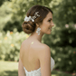 Bride wearing a white ceramic floral hair comb in an elegant half-up wedding hairstyle.