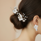 Bride wearing white porcelain flower pearl drop earrings with elegant updo and matching decorative hair pins