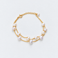Double-strand freshwater pearl bracelet with gold chains, full view on a pale grey background