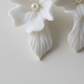 Close-up of white porcelain hydrangea earring with freshwater pearl centre and silver French hook — handcrafted wedding earrings