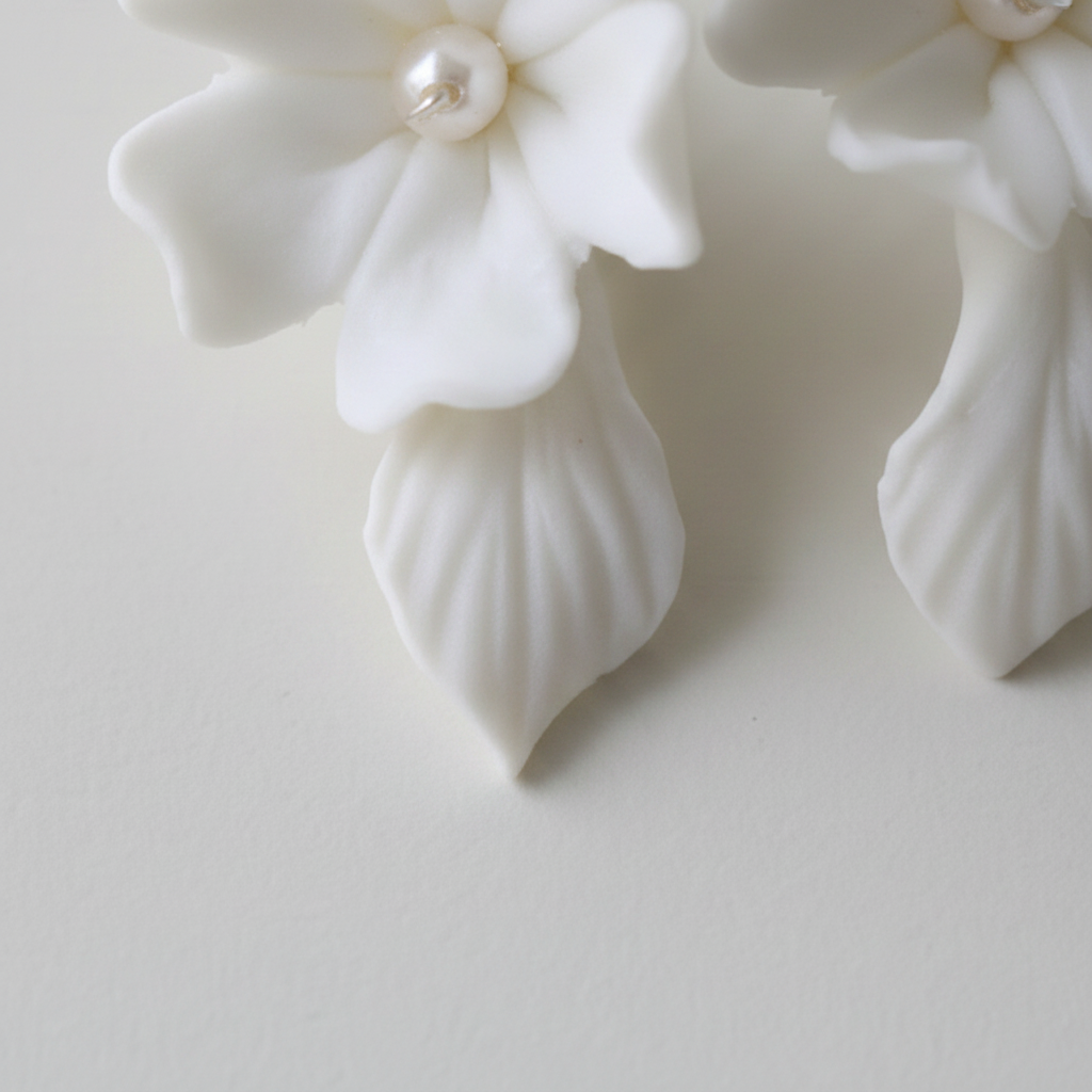 Close-up of white porcelain hydrangea earring with freshwater pearl centre and silver French hook — handcrafted wedding earrings