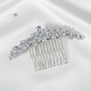 Close-up of a silver bridal hair comb with sparkling rhinestone crystals in a leaf design on a blue background