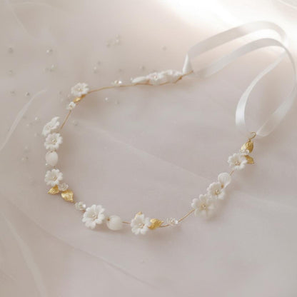 Close-up of handmade ceramic flower and imitation pearl details on gold bridal hair vine
