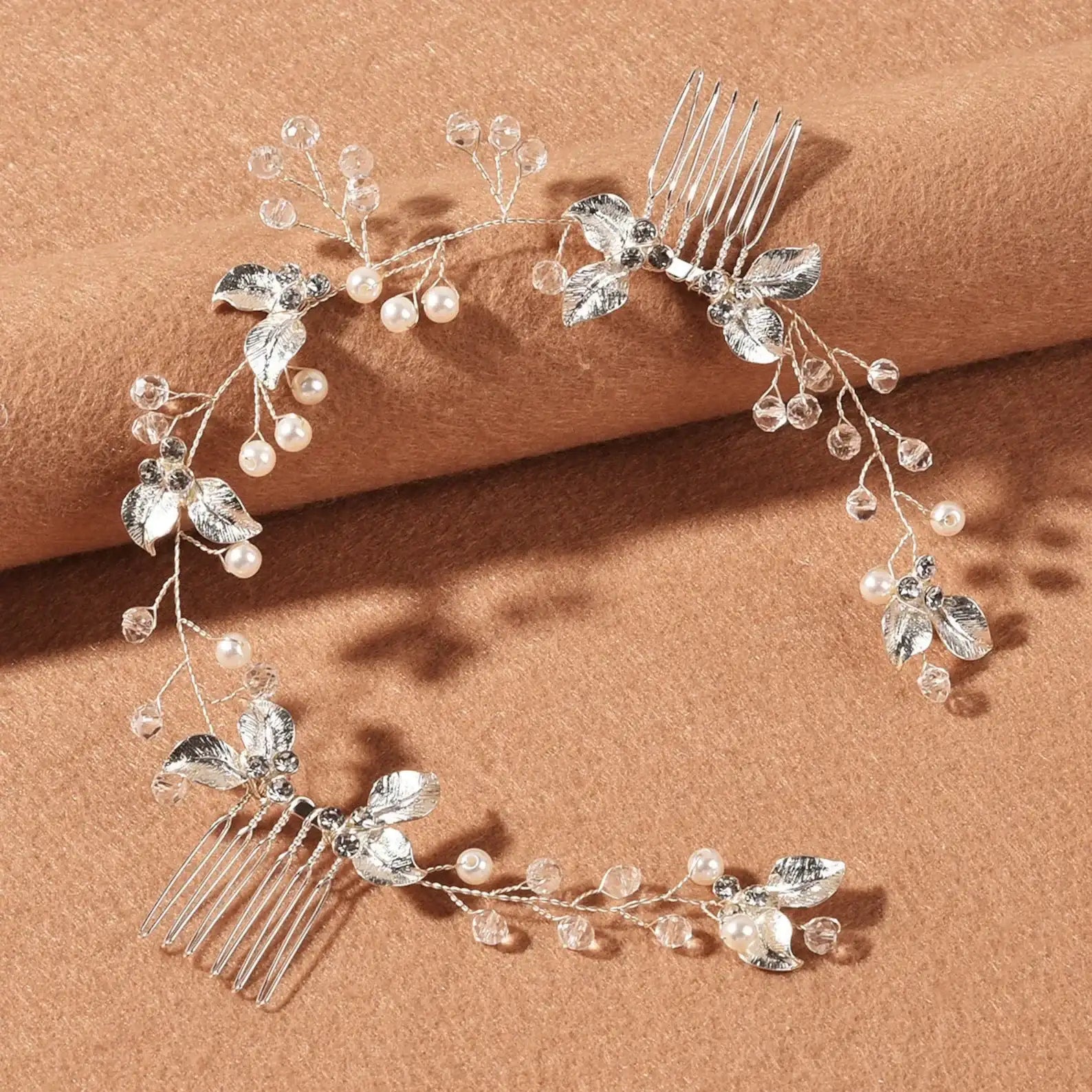 Silver bridal hair comb with pearls, crystals and leaves on a brown background