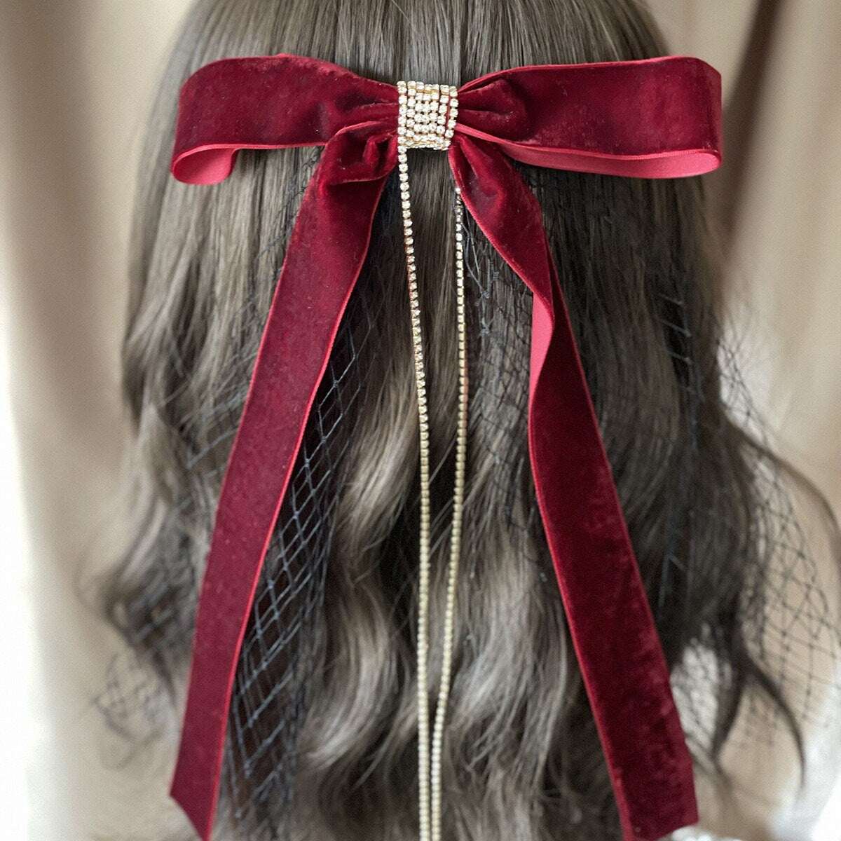 Model wearing a velvet bow hair clip with a black veil in her wavy brown hair