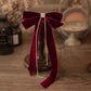 Front view of a burgundy velvet hair bow with a silver french clip and black veil