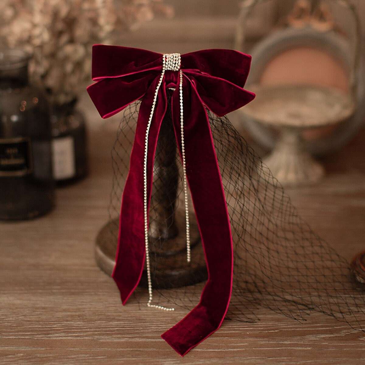 Front view of a burgundy velvet hair bow with a silver french clip and black veil