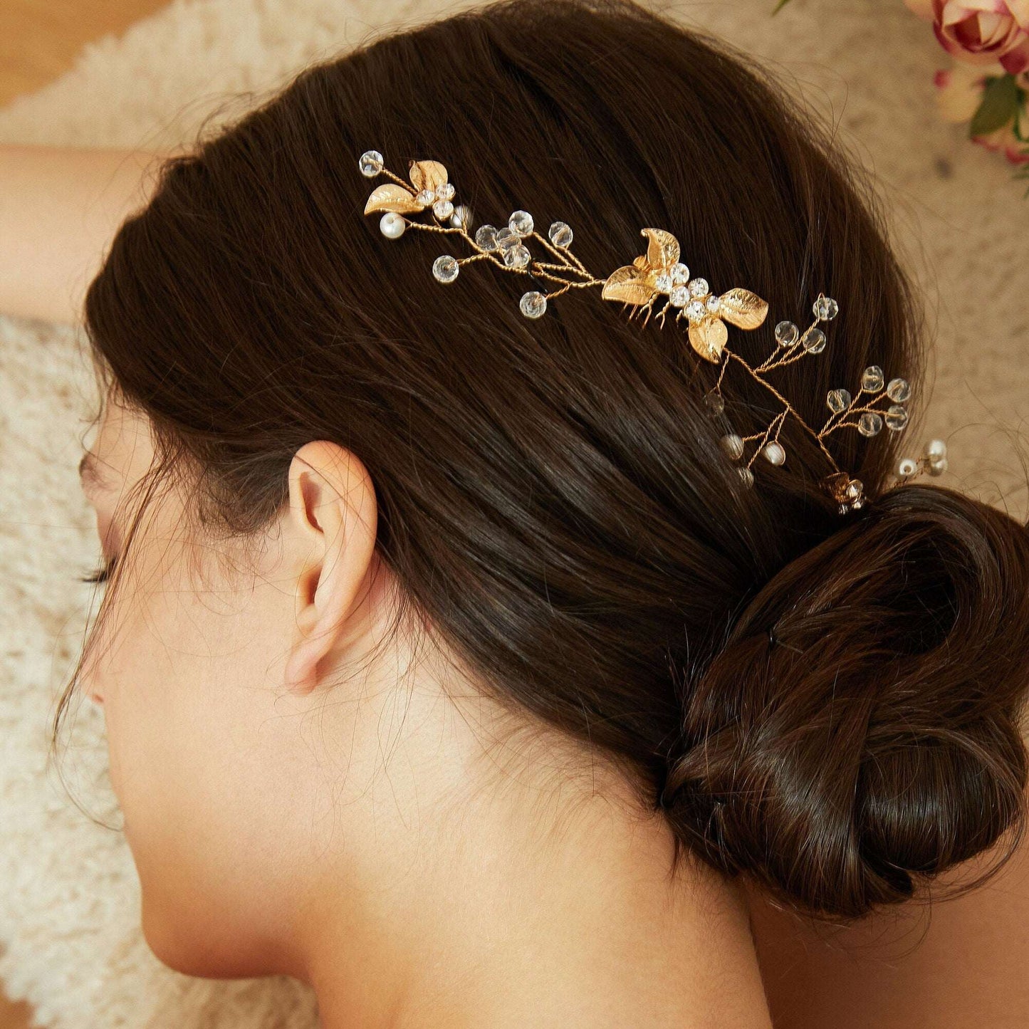 Bride wearing a delicate gold leaf hair comb with a floral background