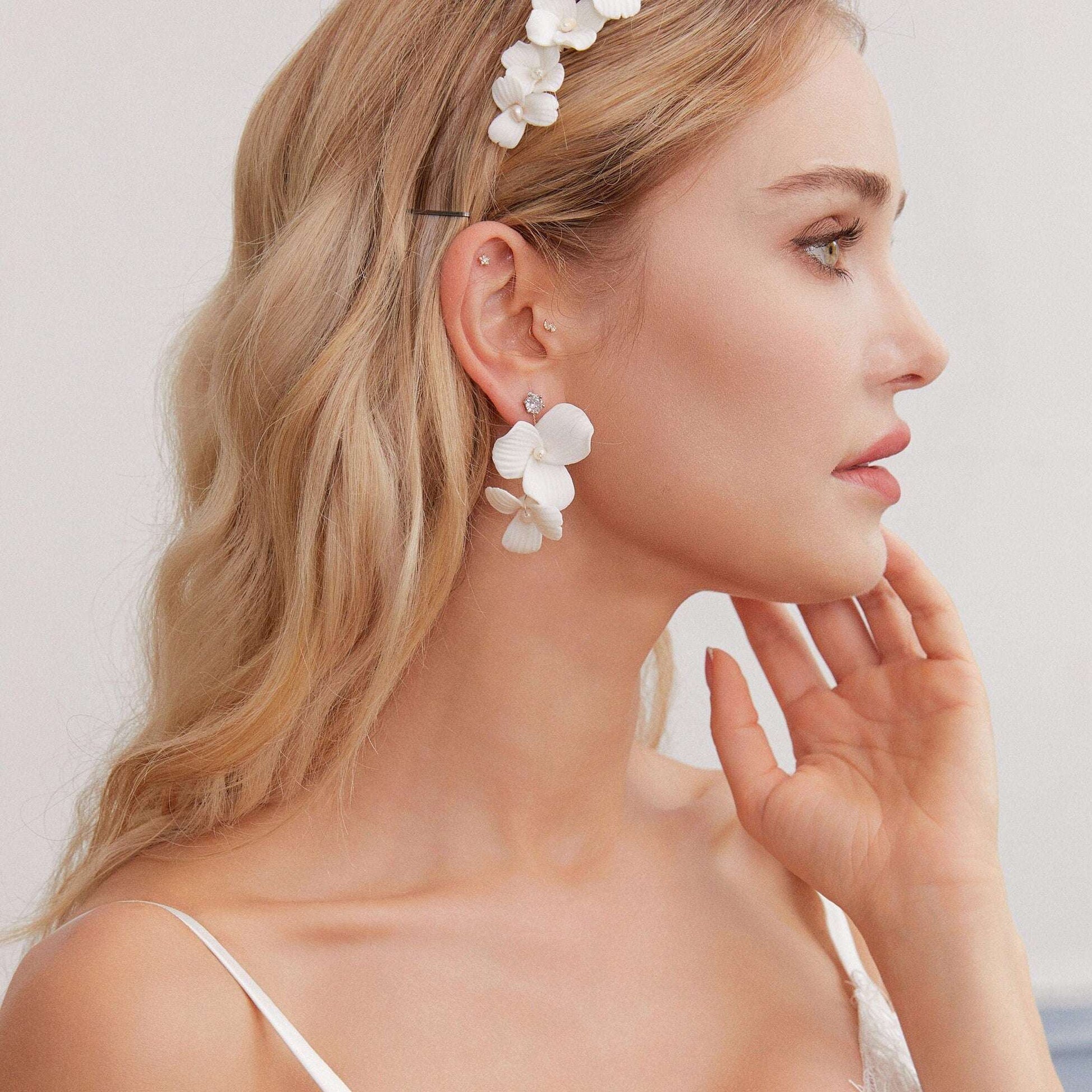 Skillfully handcrafted, these flower bridal earrings are the perfect complement to our signature porcelain headpieces. Each earring is exquisitely made by hand, featuring two delicate white clay flowers adorned with freshwater pearls.