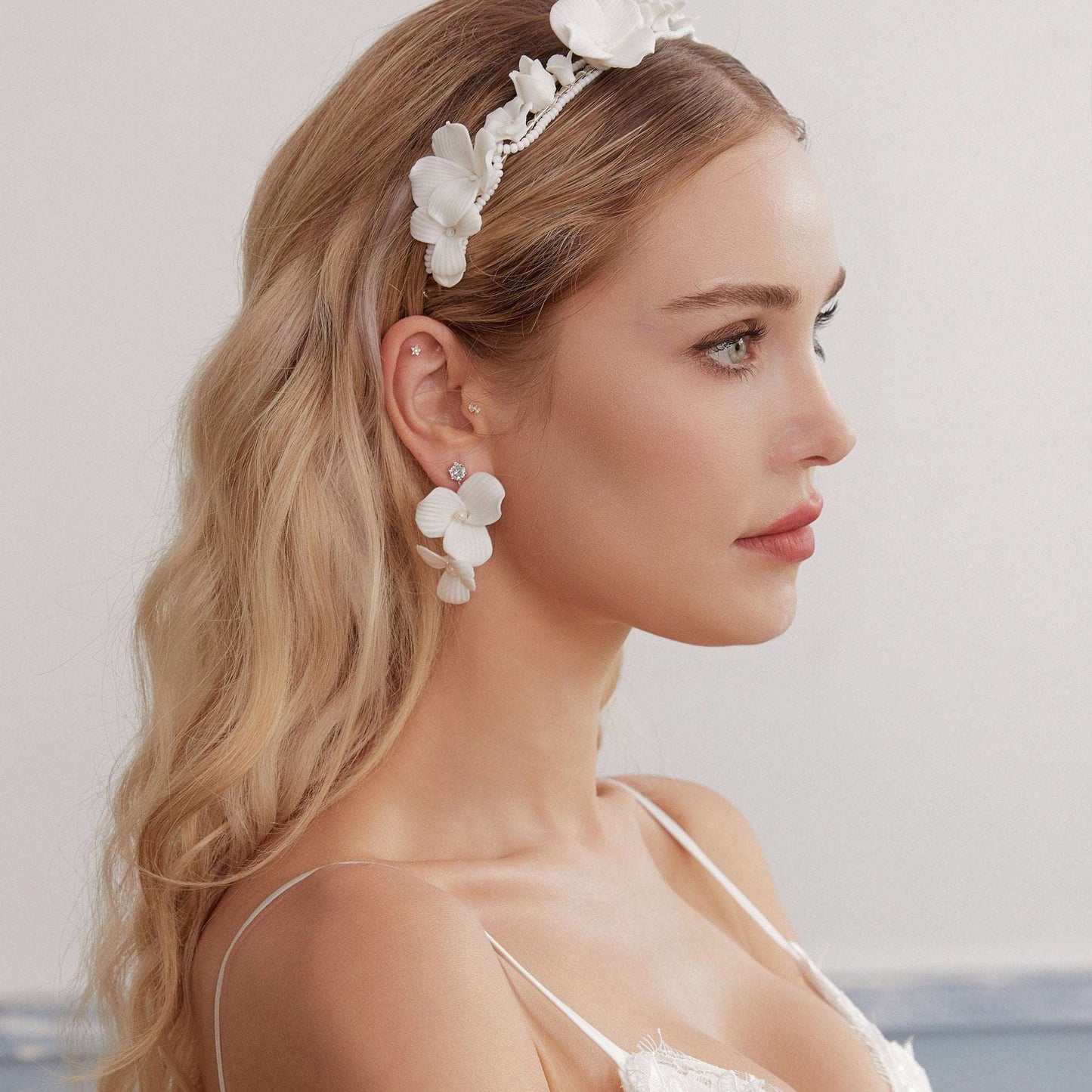 Skillfully handcrafted, these flower bridal earrings are the perfect complement to our signature porcelain headpieces. Each earring is exquisitely made by hand, featuring two delicate white clay flowers adorned with freshwater pearls.
