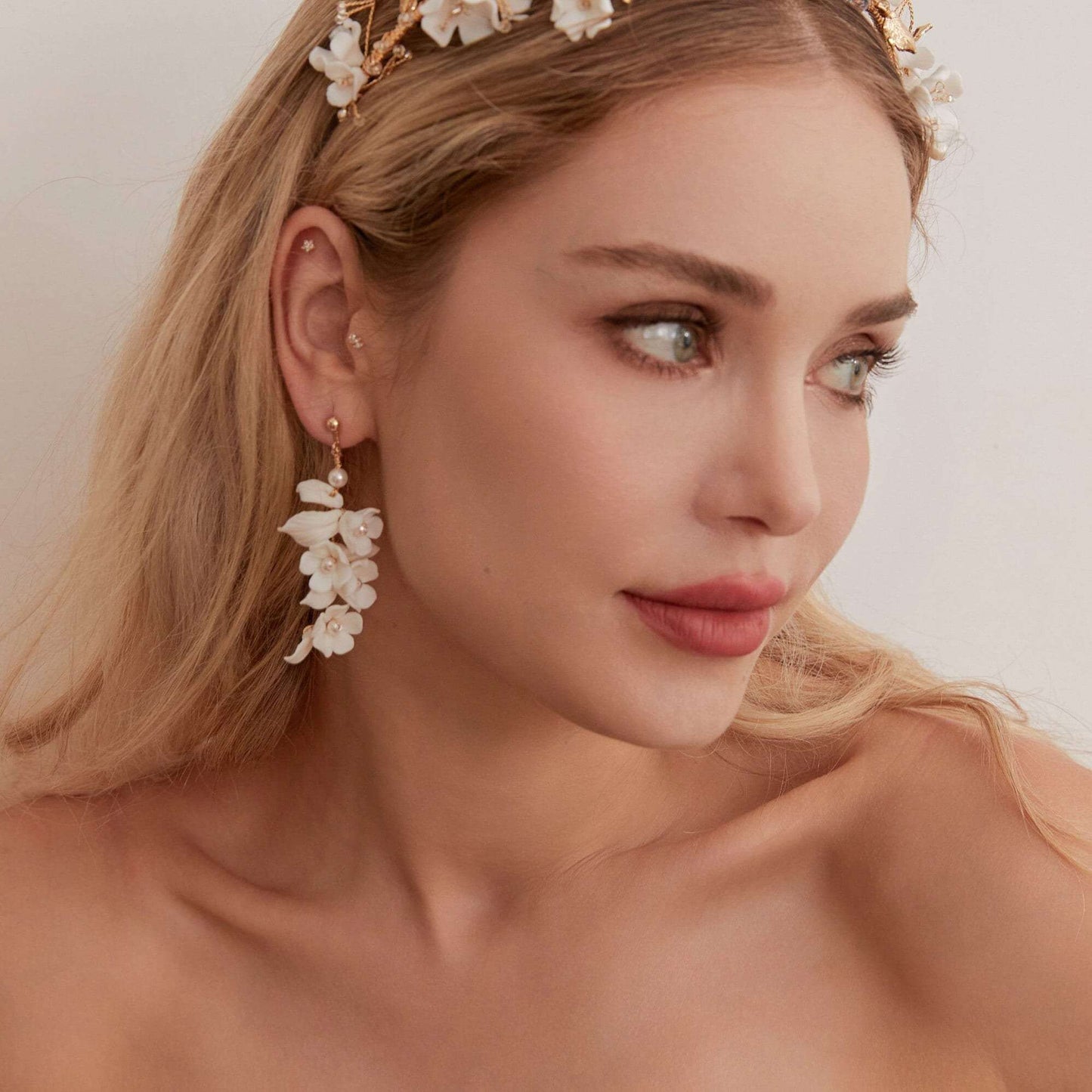 Carefully crafted by hand, these flower bridal earrings are a perfect match to our porcelain headpieces. Each earring features delicate white clay flowers and leaves adorned with shimmering freshwater pearls. These earrings have a long drop design that is sure to catch attention and make a statement.