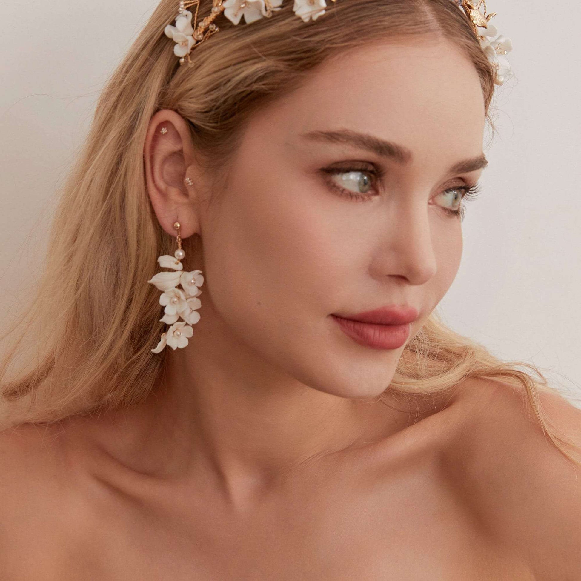Carefully crafted by hand, these flower bridal earrings are a perfect match to our porcelain headpieces. Each earring features delicate white clay flowers and leaves adorned with shimmering freshwater pearls. These earrings have a long drop design that is sure to catch attention and make a statement.