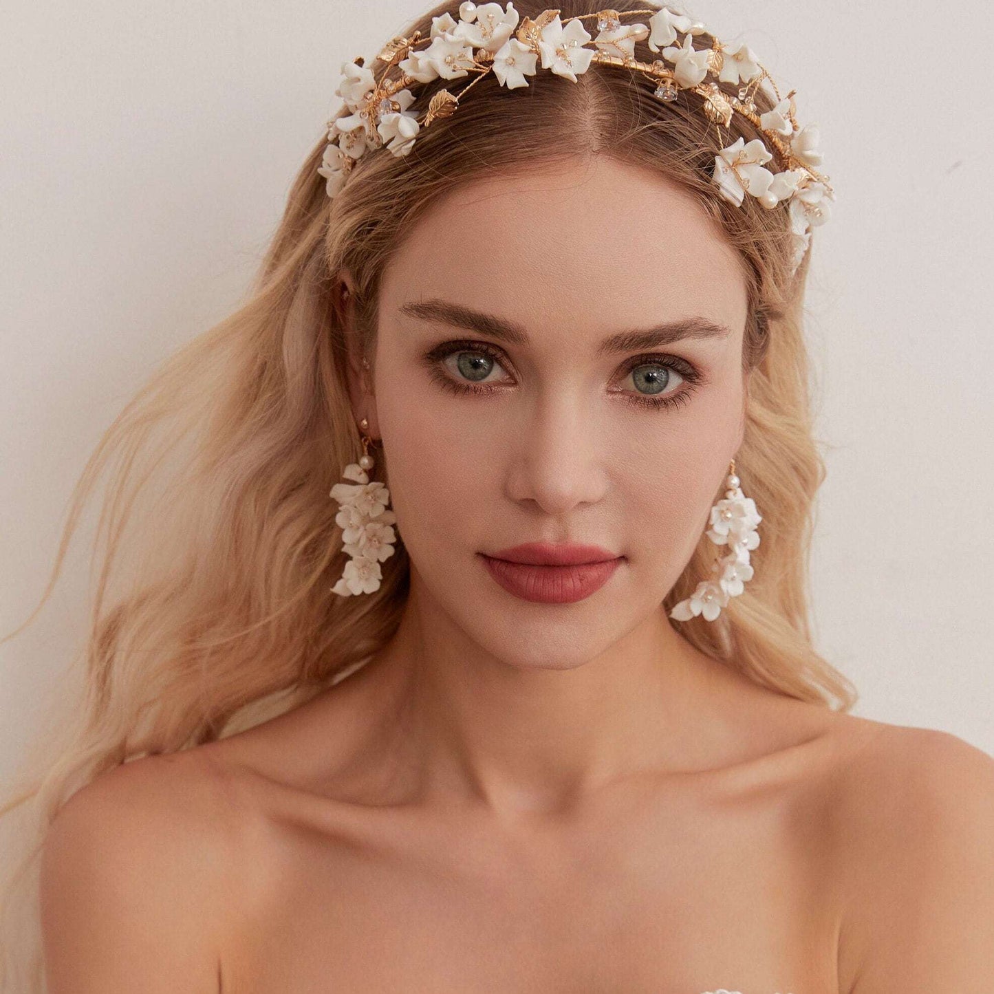 Carefully crafted by hand, these flower bridal earrings are a perfect match to our porcelain headpieces. Each earring features delicate white clay flowers and leaves adorned with shimmering freshwater pearls. These earrings have a long drop design that is sure to catch attention and make a statement.