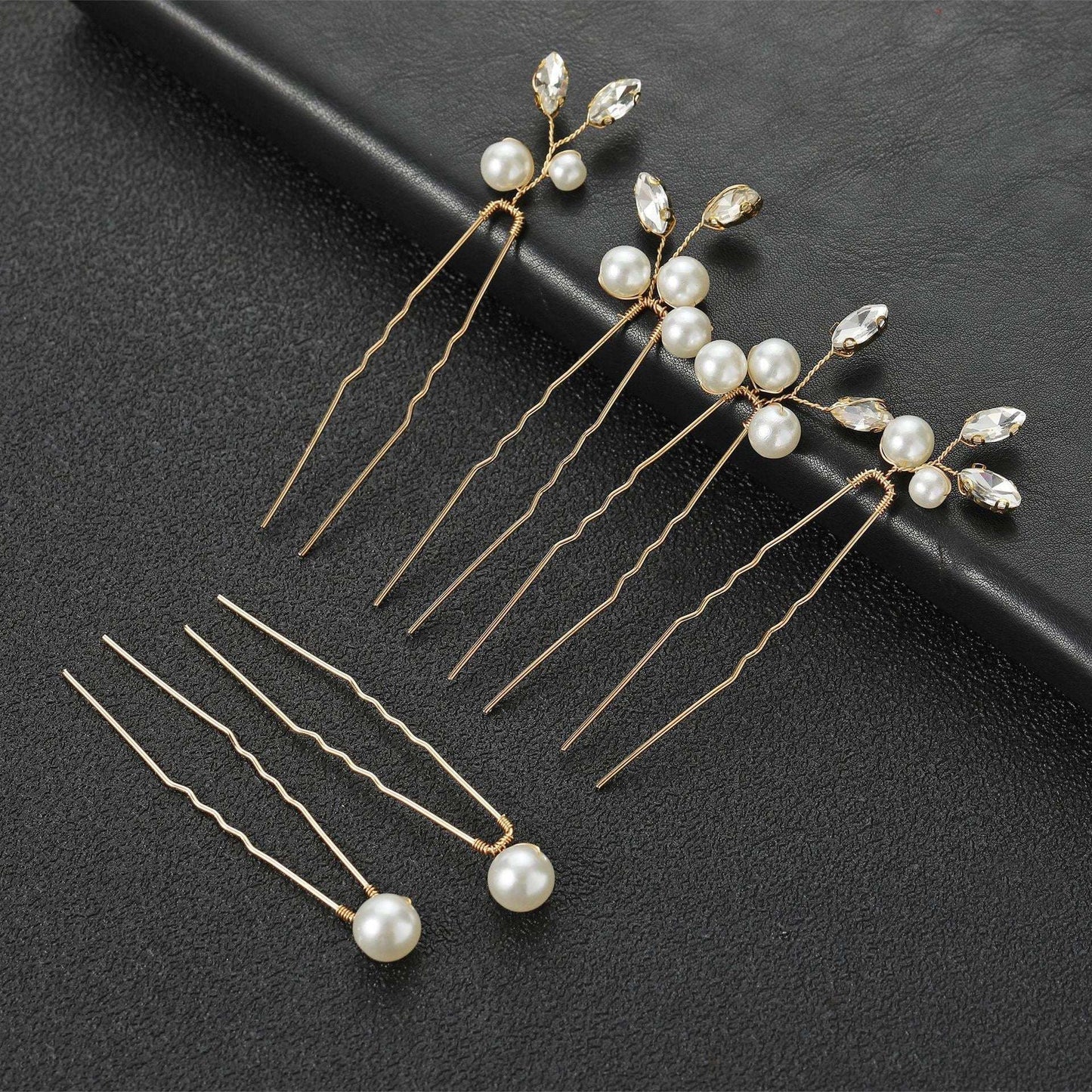 Set of 6 gold wedding hair pins with pearls and crystals arranged on a black background