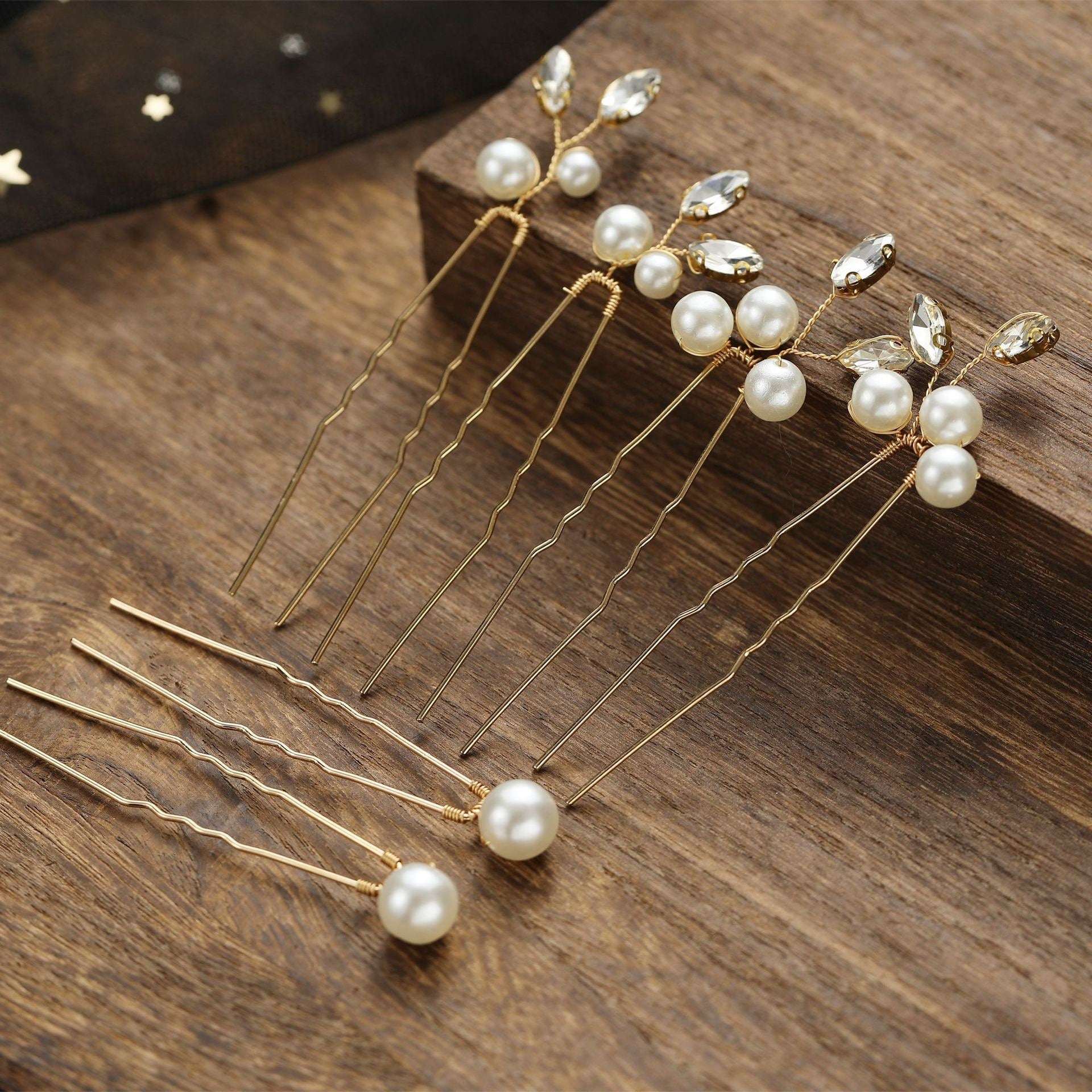 Close-up of handcrafted gold bridal hair pins with lustrous pearls on a wooden surface