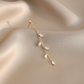14K gold olive leaf crystal drop earring macro close-up on champagne silk background