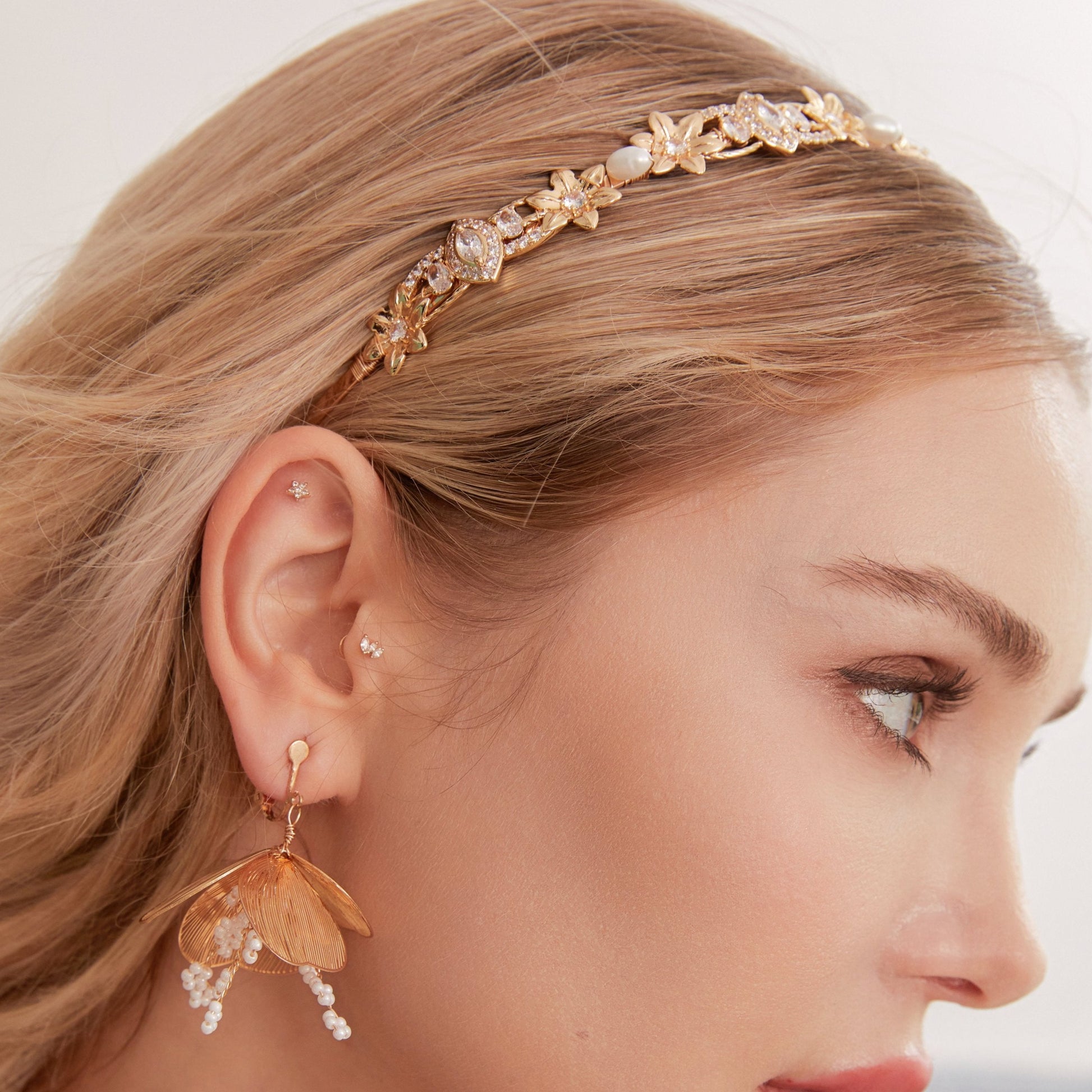 This slimline, modern gold headband is made from the most beautiful freshwater pearls and shimmering rhinestones. The minimalist floral design and timeless luxury of pearls and stones are always in style.