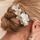 A delicate and romantic white porcelain bridal hair comb, handcrafted with love. This exquisite bridal hairpiece features a cluster of beautiful flowers adorned with lustrous natural freshwater pearls, arranged in a full design.