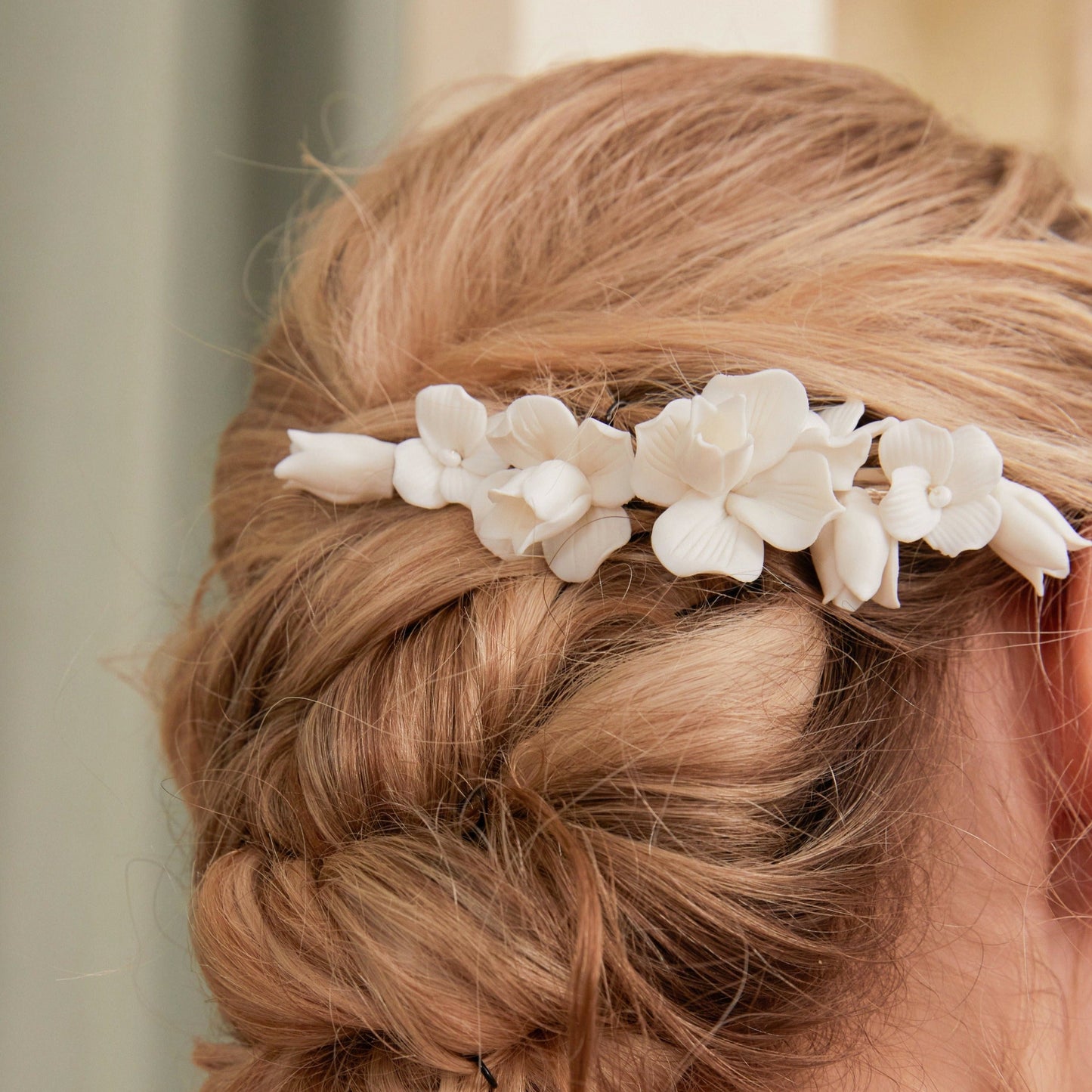 This statement bridal hair clip features carefully handcrafted white porcelain flowers and blossoms, adding an elegant and romantic touch to your hairstyle. It effortlessly enhances any bridal look, creating a timeless style.