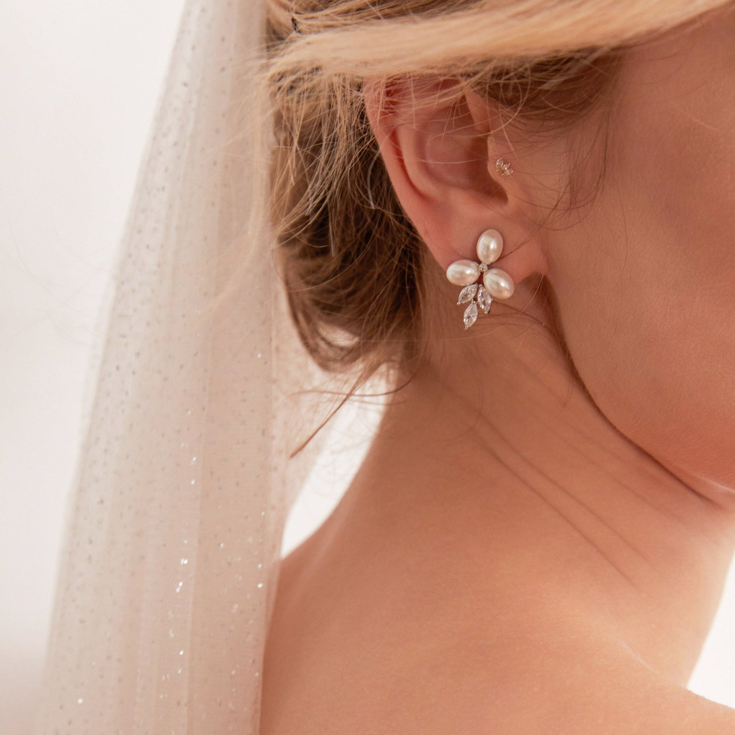 These stunning earrings feature leaf-like zirconia crystals that shimmer beneath three delicate pearls, evoking the graceful beauty of blooming flowers.