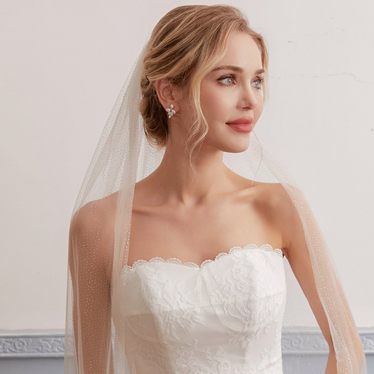 Luxurious single-layer cathedral wedding veil crafted from delicate sparkle glitter tulle. With an ivory base (also available in white and champagne), it features a simple cut edge for an elegant and timeless style that complements any bridal look.  At 3 meters long, this veil is the perfect bridal accessory to enhance any wedding dress. Offering a subtle sparkle without any fuss, it adds a touch of glamour to your special day.