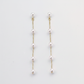 Close-up of a woman wearing delicate pearl threader earrings