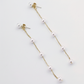 Close-up of a woman wearing delicate pearl threader earrings