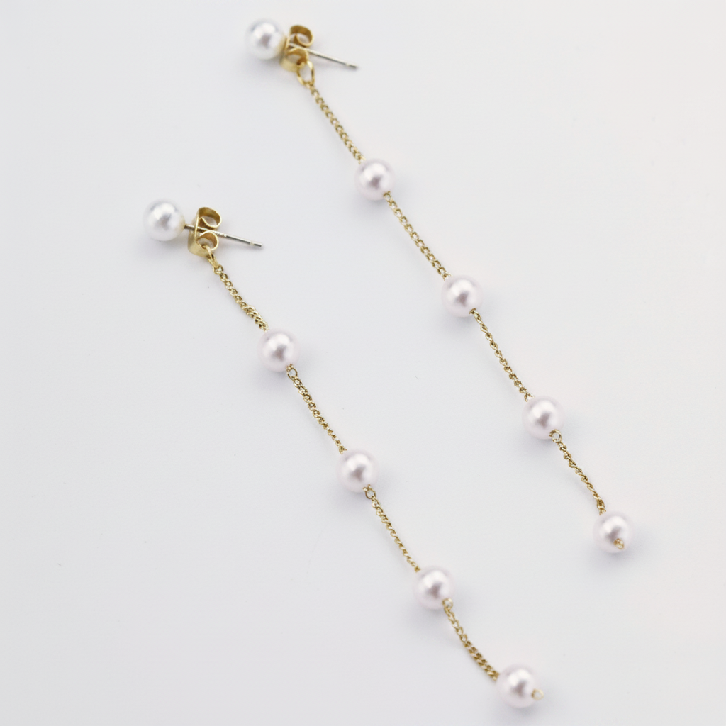 Close-up of a woman wearing delicate pearl threader earrings