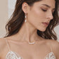 Close-up bridal portrait of a model wearing freshwater pearl tassel earrings, each with two pearls, styled with a five-pearl necklace.
