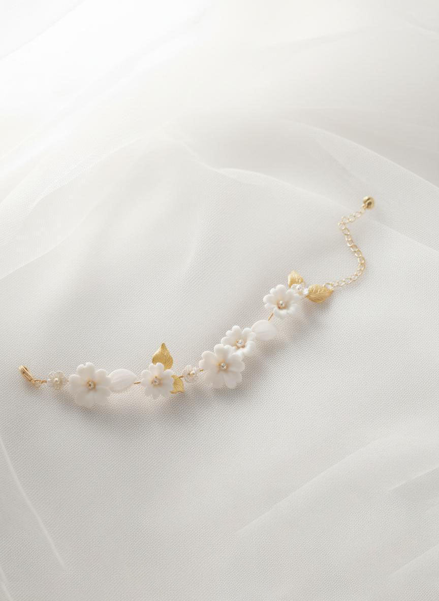 Adjustable floral bracelet with white ceramic blooms and leaf accents, gold chain bridal wrist jewellery