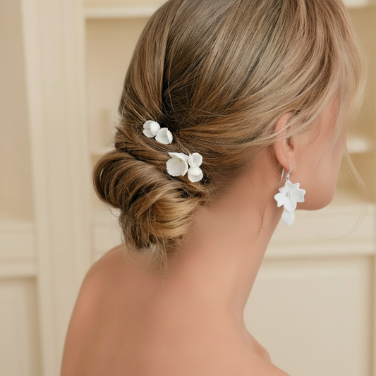 Bride wearing delicate white ceramic flower hair accessories and matching earrings for wedding day.