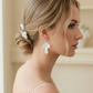 Bride in low bun hairstyle wearing white porcelain flower drop earrings and ceramic hair pins — bridal accessory set
