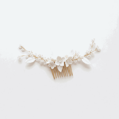 Close up of delicate white porcelain flower petals and lustrous pearl accents on a gold tone bridal hair comb