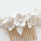 Close up of delicate white porcelain flower petals and lustrous pearl accents on a gold tone bridal hair comb.