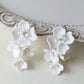 Handmade white porcelain flower earrings with crystal studs on a white surface
