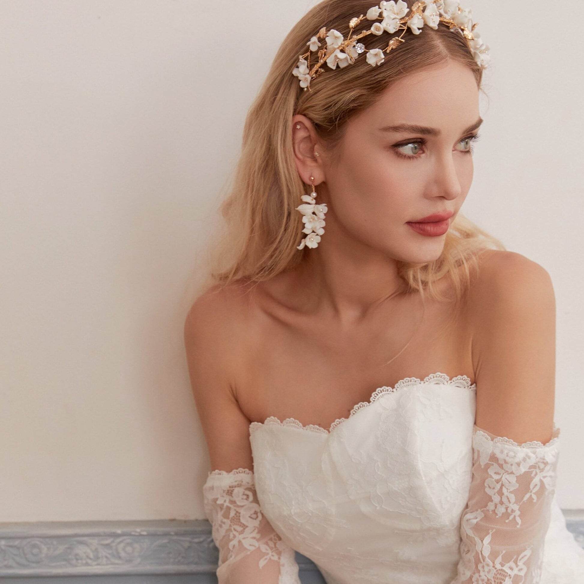 Carefully crafted by hand, these flower bridal earrings are a perfect match to our porcelain headpieces. Each earring features delicate white clay flowers and leaves adorned with shimmering freshwater pearls. These earrings have a long drop design that is sure to catch attention and make a statement.
