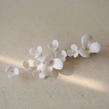 Close-up of the LILLIAN gold bridal hairpin with white porcelain flowers